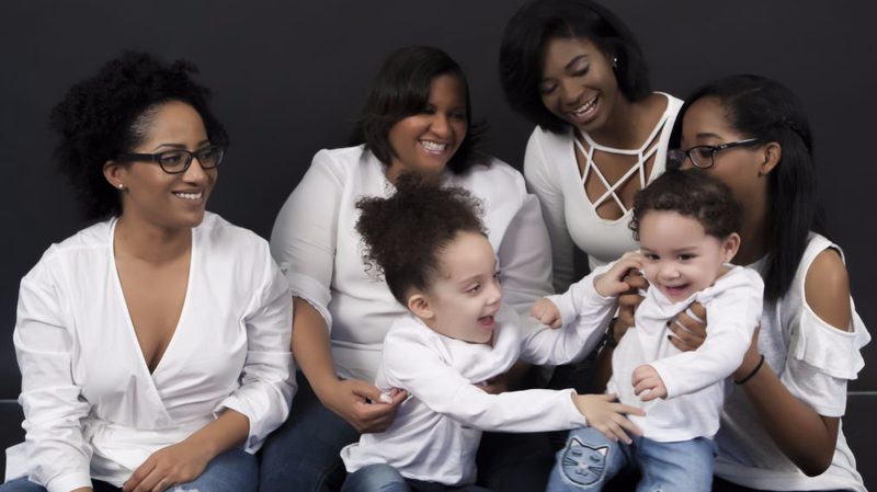 Family of women and two toddlers laughing together in the studio