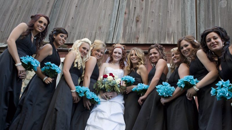 Bride and bridesmaids with turquoise bouquets in front of a barn
